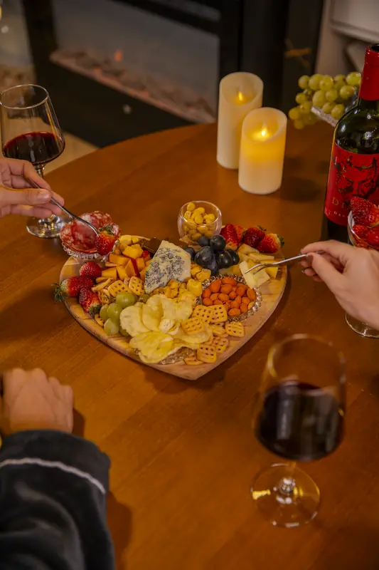 Tábua de frios em formato de coração, com frutas, velas e vinho
