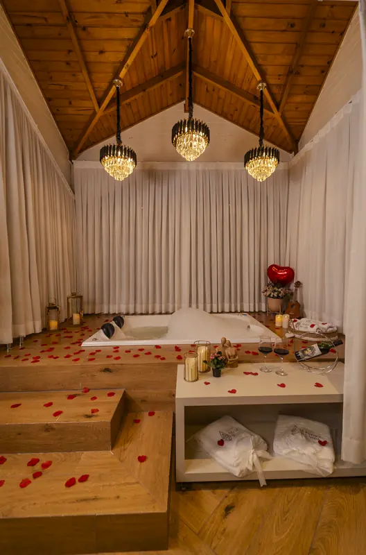 A banheira de hidromassagem decorada com pétalas vermelhas, velas e um balão de coração