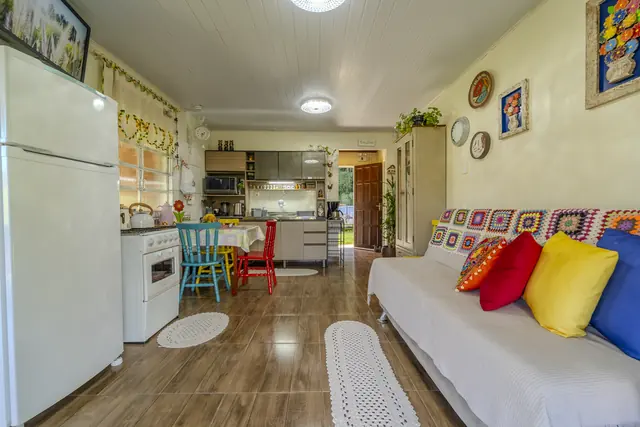 Sala colorida com sofá, almofadas de crochê e cozinha integrada