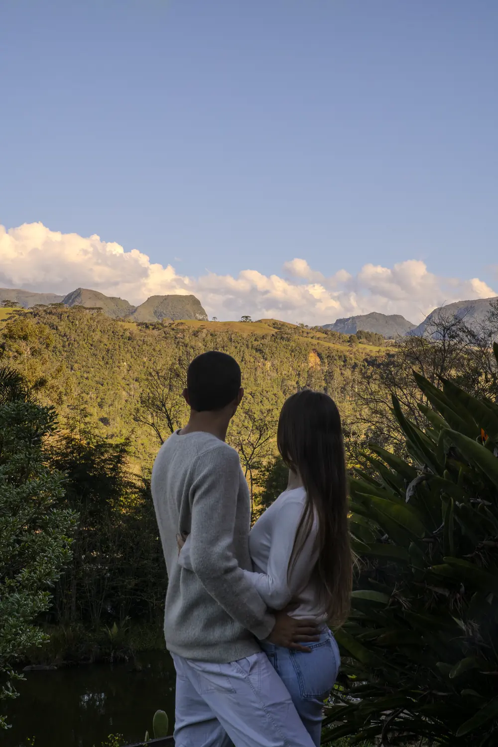 Casal abraçado olhando a serra ao pôr do sol