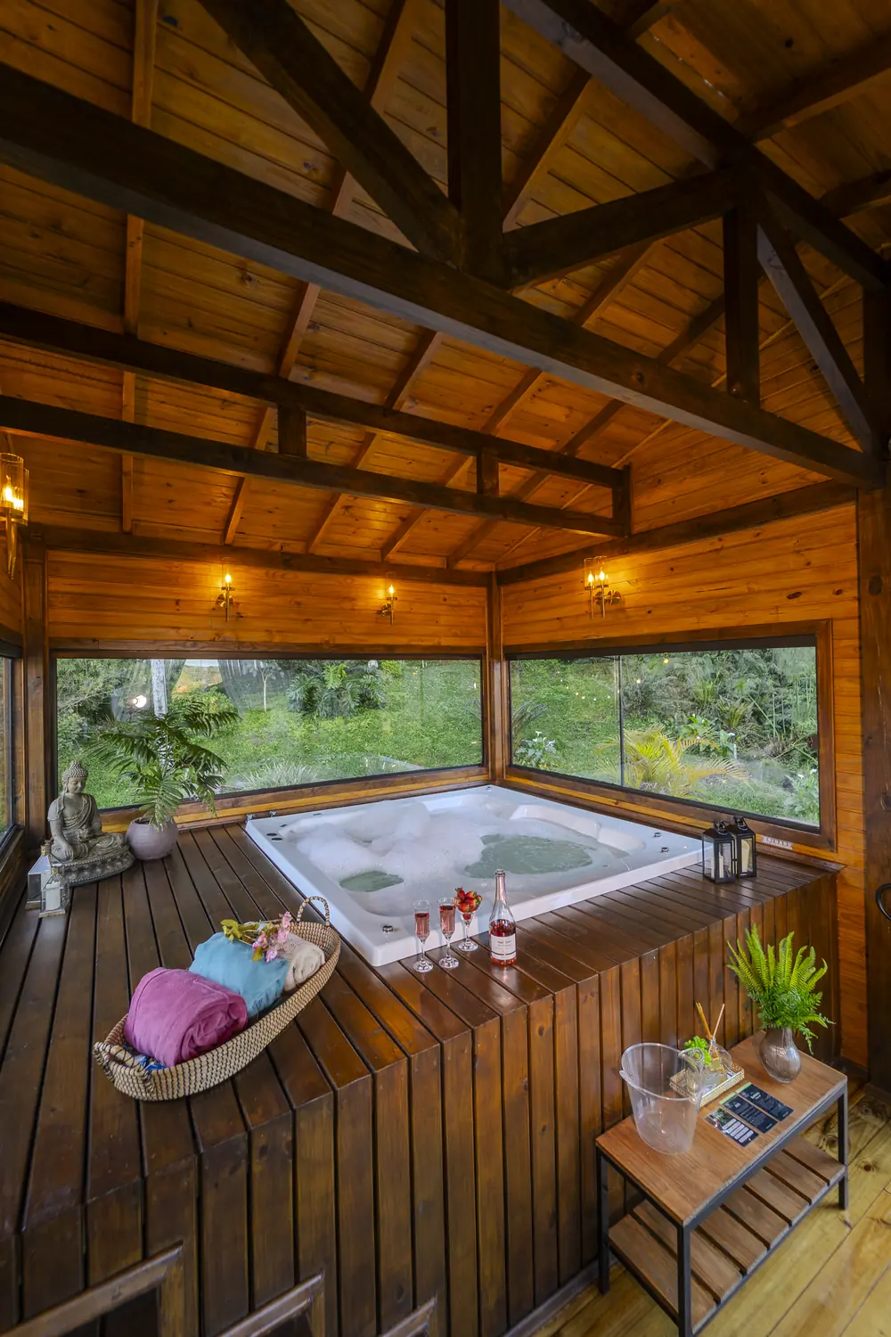 Jacuzzi do spa visto de cima, com o deck de madeira e os janelões para a mata